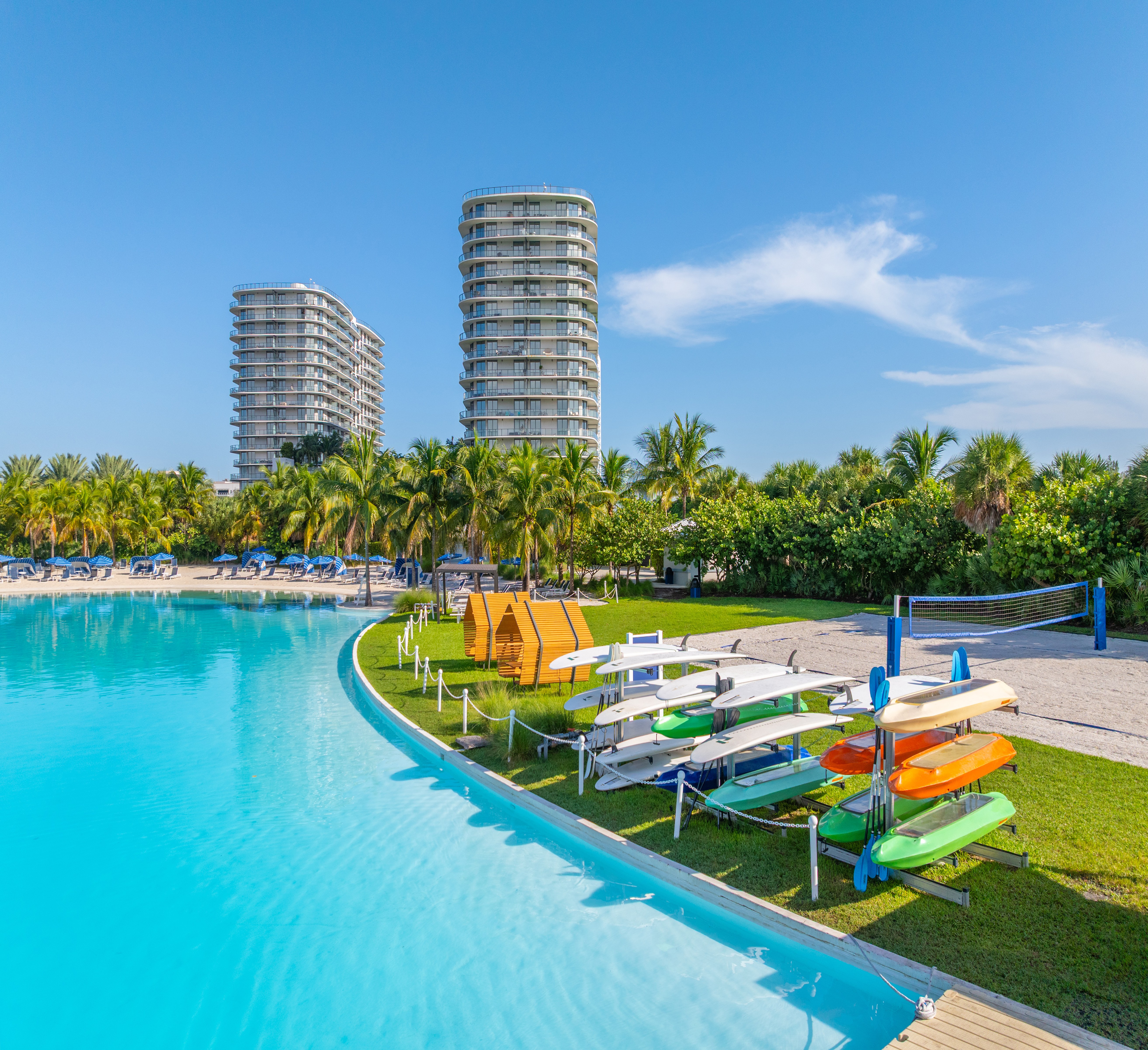 A pool with a row of sun loungers and a row of buildings in the background.